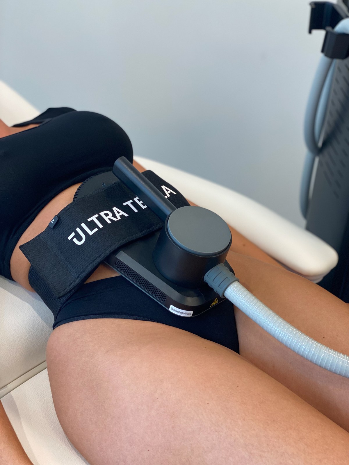 Ultra Tesla Sculpt applicator secured over an abdomen during treatment